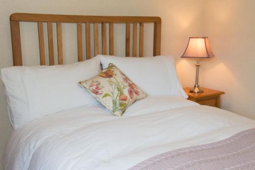 洛克比Bishopcleugh Guest House的一张带枕头的白色床和一盏灯