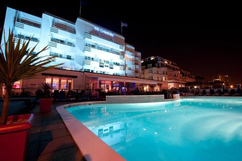 伯恩茅斯坎伯兰海洋休闲酒店的一座游泳池,在晚上在建筑物前