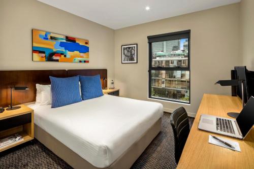墨尔本Quest Docklands的酒店客房配有一张床、一张书桌和一台笔记本电脑