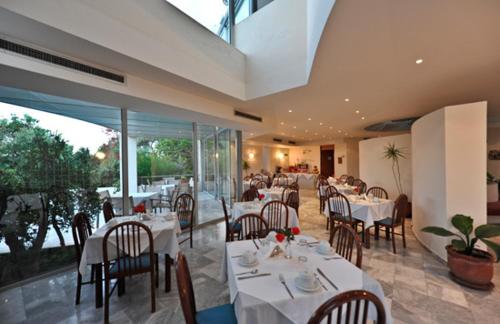 干尼亚罗登酒店的餐厅设有白色的桌椅和玻璃墙