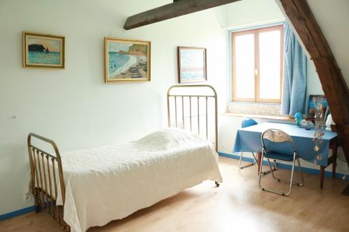 曼尼克维尔Chambres d'Hôtes " Le Clos des Colimaçons "的一间卧室配有一张床、一张书桌和一个窗户。
