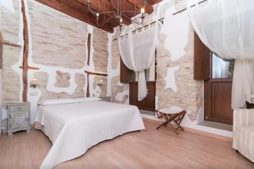 卡利亚里雅倩旅馆的卧室配有白色的床和石墙