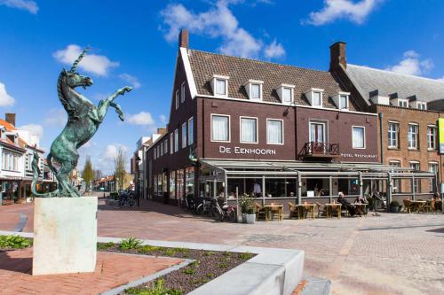 奥斯特堡De Eenhoorn的街道中间的雕像,有建筑