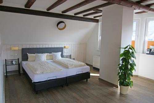 埃伦茨-波尔特斯多夫豪斯曼旅馆的一间卧室配有一张大床和盆栽植物
