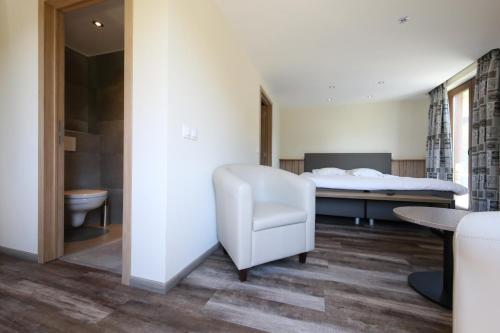 斯塔沃洛沃德拉喀斯特酒店的一间卧室配有一张床和一张白色椅子