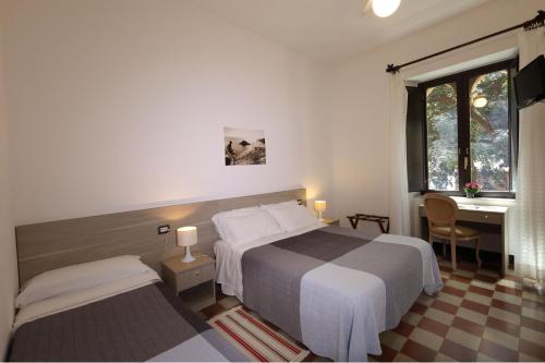 陶尔米纳阿斯托利亚别墅酒店的酒店客房配有两张床、一张书桌和一张书桌。