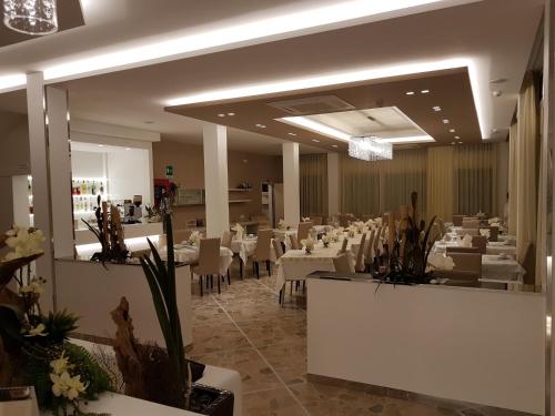 切塞纳蒂科索尔马尔酒店的用餐室配有白色的桌子和白色的椅子