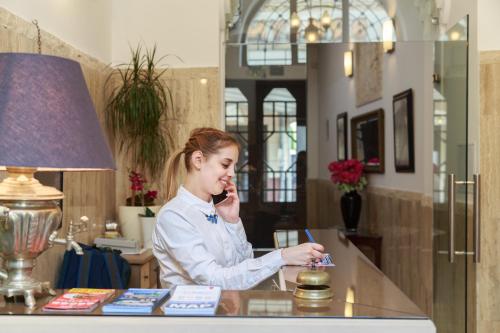 布达佩斯Hotel Mika Downtown的坐在一张桌子上,在手机上说话的女人