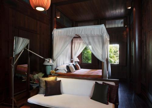 曼谷查克洛博瑟别墅酒店的一间卧室配有天蓬床和白色沙发
