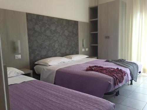 里米尼雷登斯酒店的酒店客房,配有两张带紫色床单的床