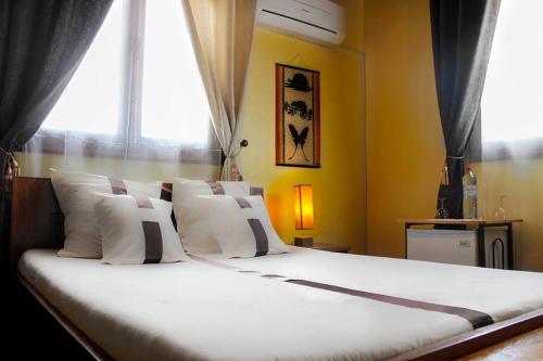 塔那那利佛意阿瑞姆巴托酒店的一张带白色枕头的大床和窗户