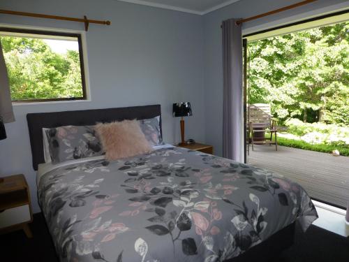 陶朗加Tranquil Private Rural Retreat的一间卧室设有一张床和一个带庭院的窗户。