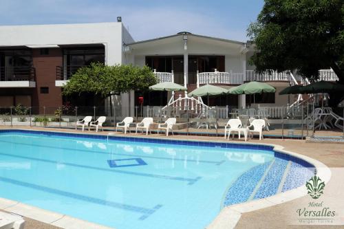 梅尔加Hotel Restaurante Versalles的一个带白色椅子和遮阳伞的大型游泳池
