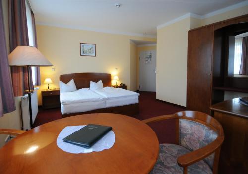 德伯尔恩霍夫德伯尔恩酒店的酒店客房设有一张床和一张桌子,上面有一台笔记本电脑