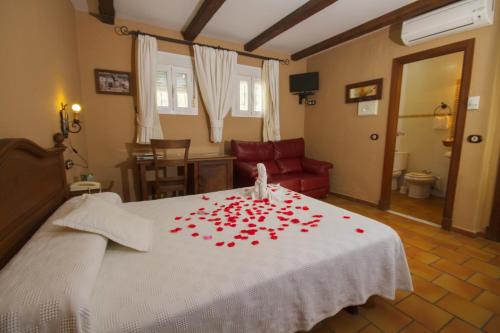 埃尔博斯克埃尔塔本克酒店的一间卧室配有一张白色的床铺,上面有红玫瑰