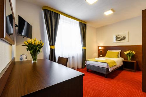 华沙L26 Łopuszańska的酒店客房,配有床和鲜花书桌