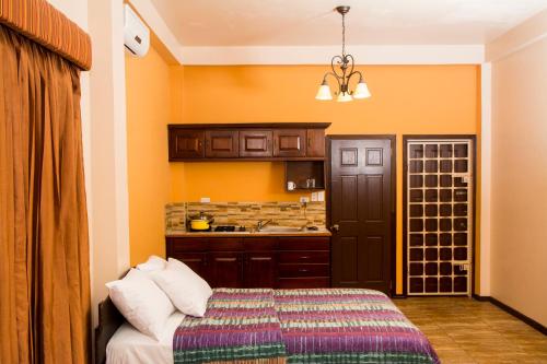 乔治敦Windjammer International Cuisine & Comfort Inn的一间设有床铺的客房和一间带橙色墙壁的厨房
