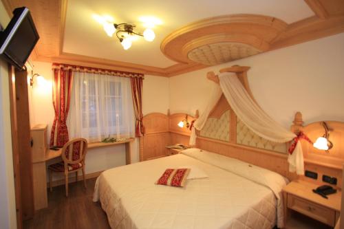 卡纳泽伊Garnì Val de Costa的一间卧室配有一张床、一张书桌和一台电视