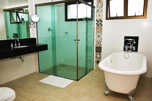 乌贝拉巴Tamareiras Prime Hotel的一间带玻璃淋浴和浴缸的浴室
