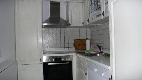 加尔米施-帕滕基兴Apartment Xenia的厨房配有白色橱柜和炉灶烤箱。