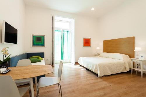 索伦托科索意大利套房酒店的一间卧室配有一张床铺和一张桌子,还有一间用餐室