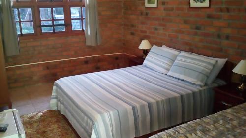 圣弗朗西斯科-迪保拉Pousada Refúgio do Lago的一间卧室设有一张床和砖墙