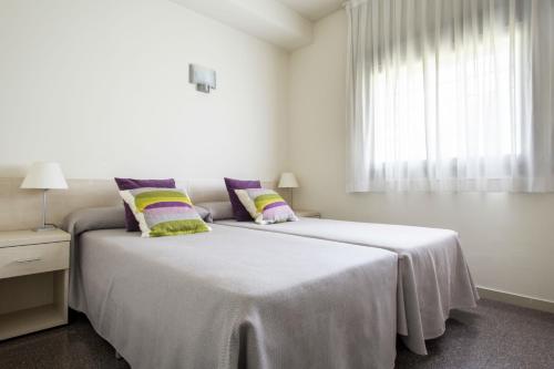 潘普洛纳桦树大学旅馆的一间白色卧室,配有两张床和窗户