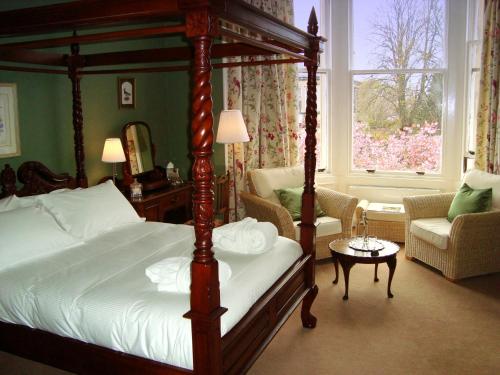 艾尔Lochinver Guesthouse的一间带天蓬床的卧室和一间客厅