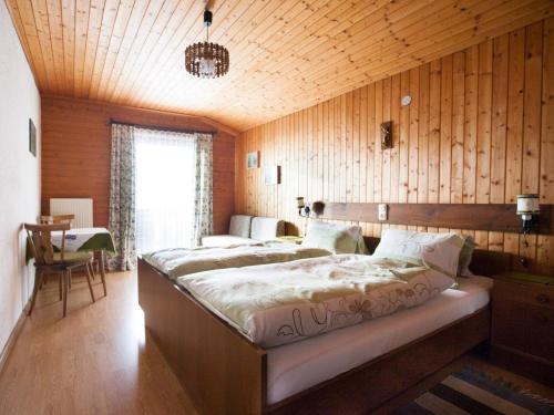 韦尔芬厄赫腾巴古提有机农场酒店的一间带两张床铺的卧室,位于带木墙的房间内