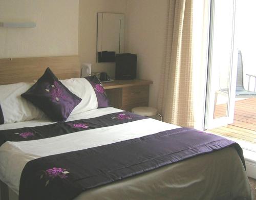 纽基Harrington Guest House的一间卧室配有一张带紫色和白色枕头的床