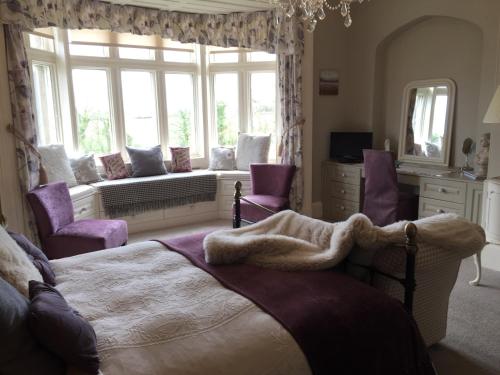 哈罗盖特哈泽尔庄园酒店的一间卧室配有一张带紫色椅子的床和窗户。