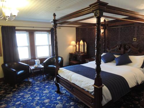 柯克沃尔The Orkney Hotel的一间卧室配有一张天蓬床和两把椅子