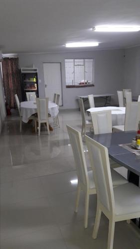 比勒陀利亚山谷住宿加早餐旅馆的用餐室配有白色的桌子和白色的椅子