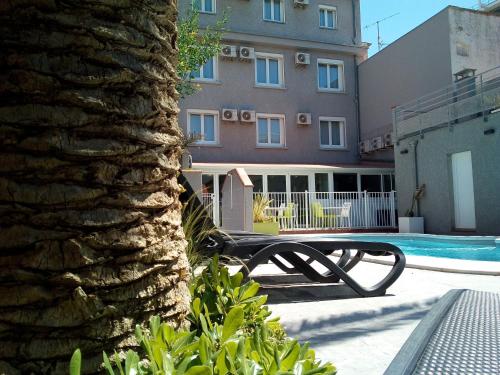 鲁西隆地区卡内Hotel Le Majestic Canet plage的大楼前的长凳,带游泳池