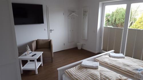 比苏姆Hotel Dorfkrug Büsum的白色的客房配有床、椅子和电视