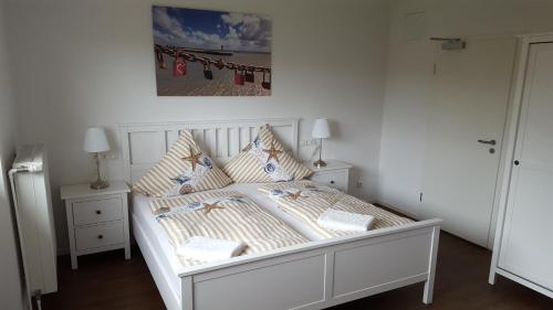 比苏姆Hotel Dorfkrug Büsum的一张带枕头的白色床和墙上的照片
