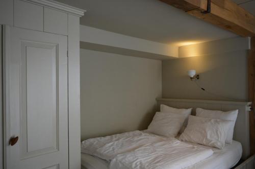 蒙尼肯丹Waterland Achterhuis的一张带白色床单和枕头的床