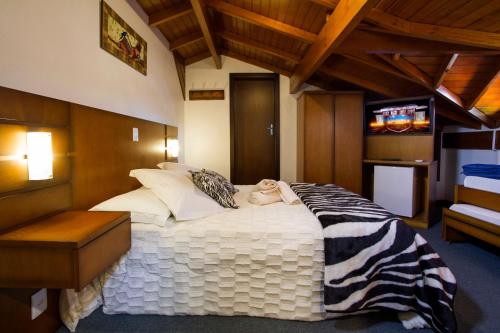 卡内拉Pousada Hencke Haus的一间卧室配有一张大床和斑马毯