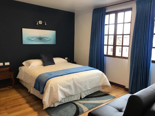 基多厄瓜宝藏历史中心酒店的一间卧室配有蓝色窗帘的床