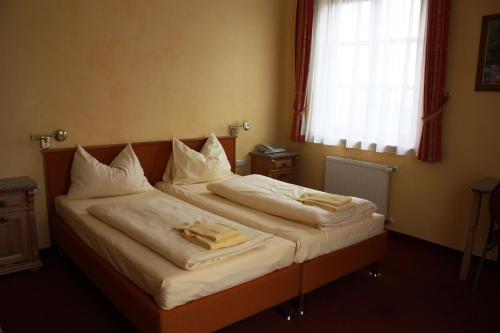 ZöbernAutobahnrestaurant & Motorhotel Zöbern的一间卧室设有两张带白色床单的床和窗户。