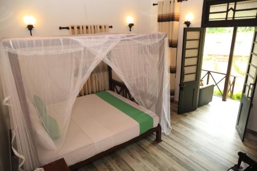 平纳瓦拉宾那伟拉别墅及餐厅的一间卧室配有一张带蚊帐的床