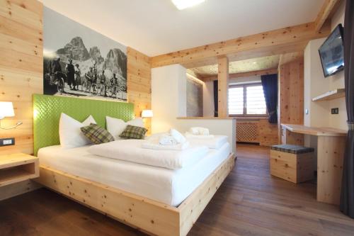 泰塞罗DOLOMITES B&B - Suites, Apartments and SPA的一间带一张大床的卧室,位于带木墙的房间