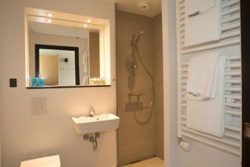 森讷堡6400酒店的浴室配有盥洗盆和带镜子的淋浴