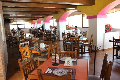 Xicotepec de JuárezHotel Villa de Cortez的餐厅设有木桌和椅子,客人坐在桌子旁