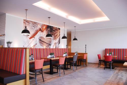 帕德博恩IBB Hotel Paderborn的餐厅设有桌椅,墙上挂有绘画作品