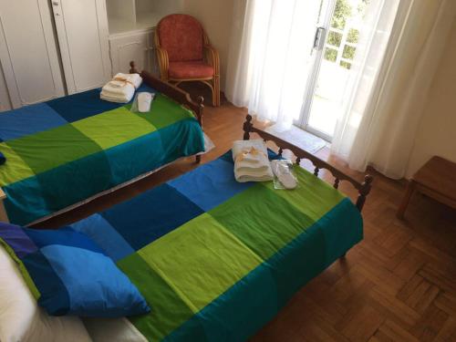 马科普隆Apartment in Markopoulo center的一间卧室设有两张床、一把椅子和一个窗户。