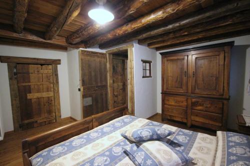 奥斯塔Vecchio Fienile的一间卧室设有一张床、木制天花板和木制橱柜。