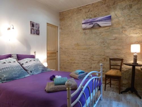 萨尔拉拉卡内达Appartement centre médiéval - Le Cosy de Sarlat的一间卧室配有一张紫色的床和石墙