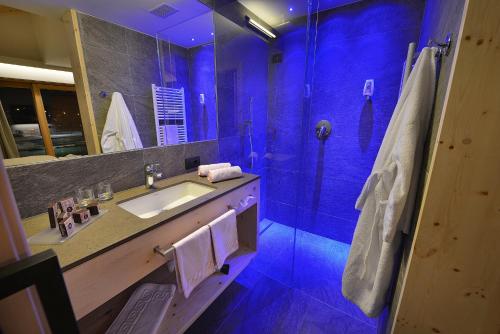 利维尼奥Hotel Roberta Alpine Adults only的浴室配有水槽和带蓝色灯光的淋浴