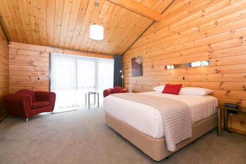 新普利茅斯洛克伍德庄园汽车旅馆的木制客房内的一间卧室,配有一张床